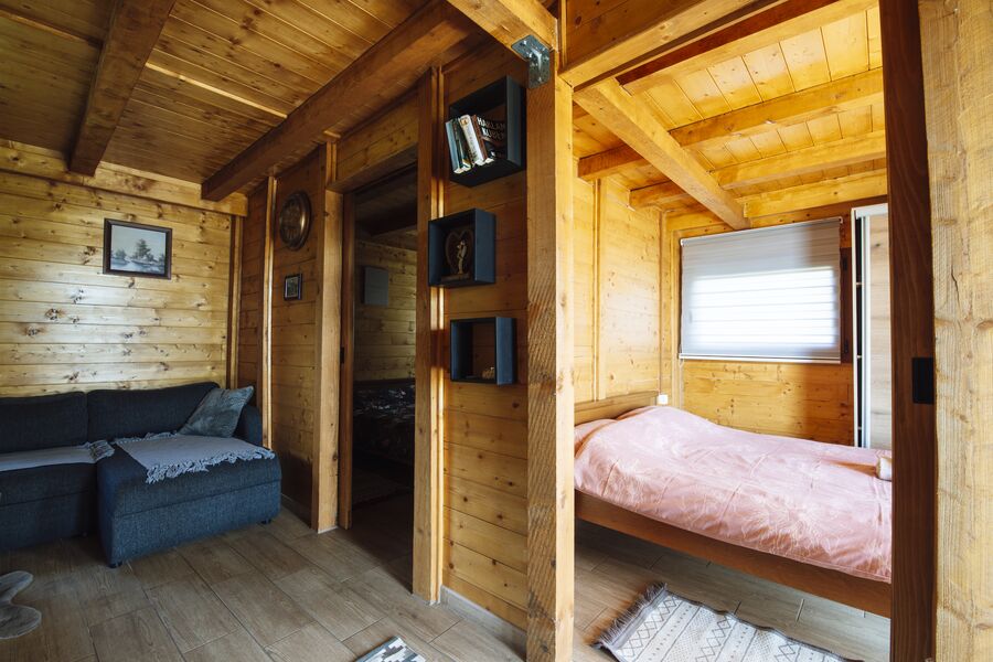 Cabin interior with a wooden ceiling, a sofa and a made bed